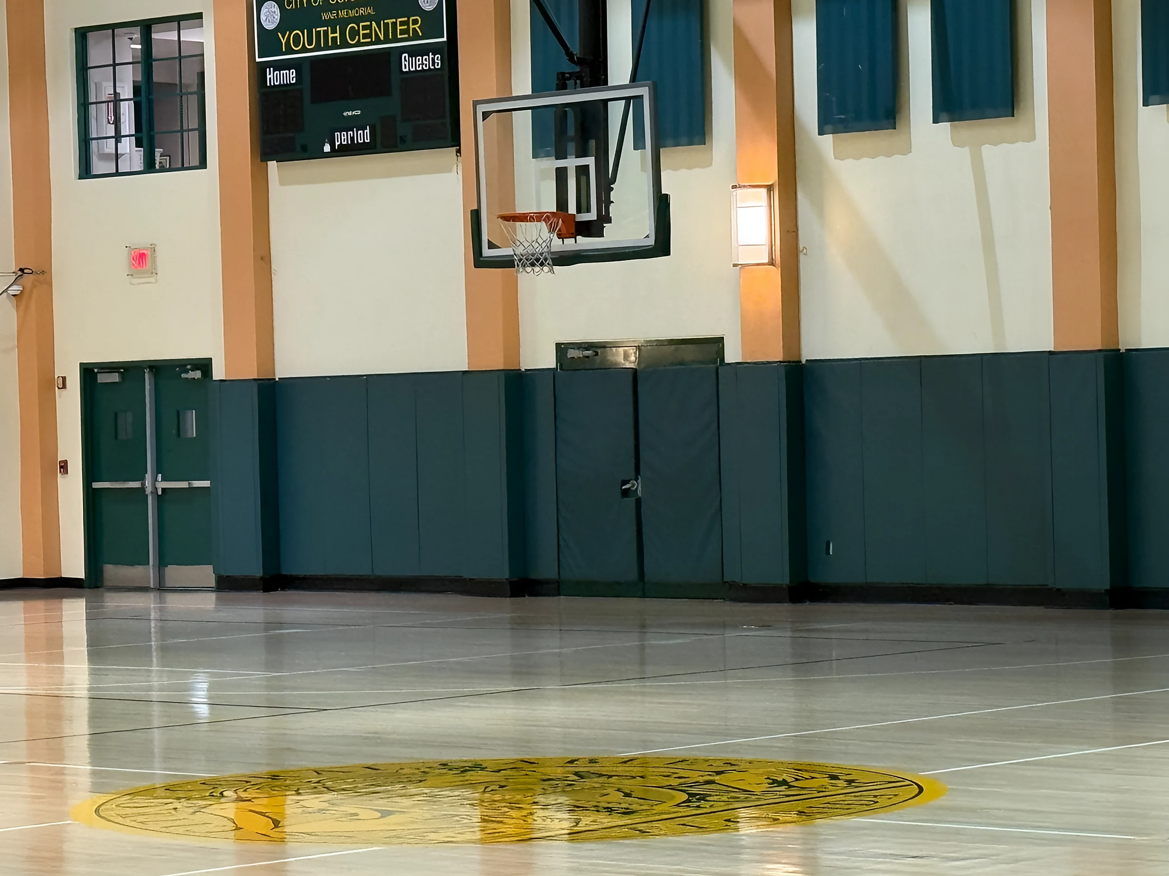 Center-court seal under the Youth Center scoreboard, with new green wall pads