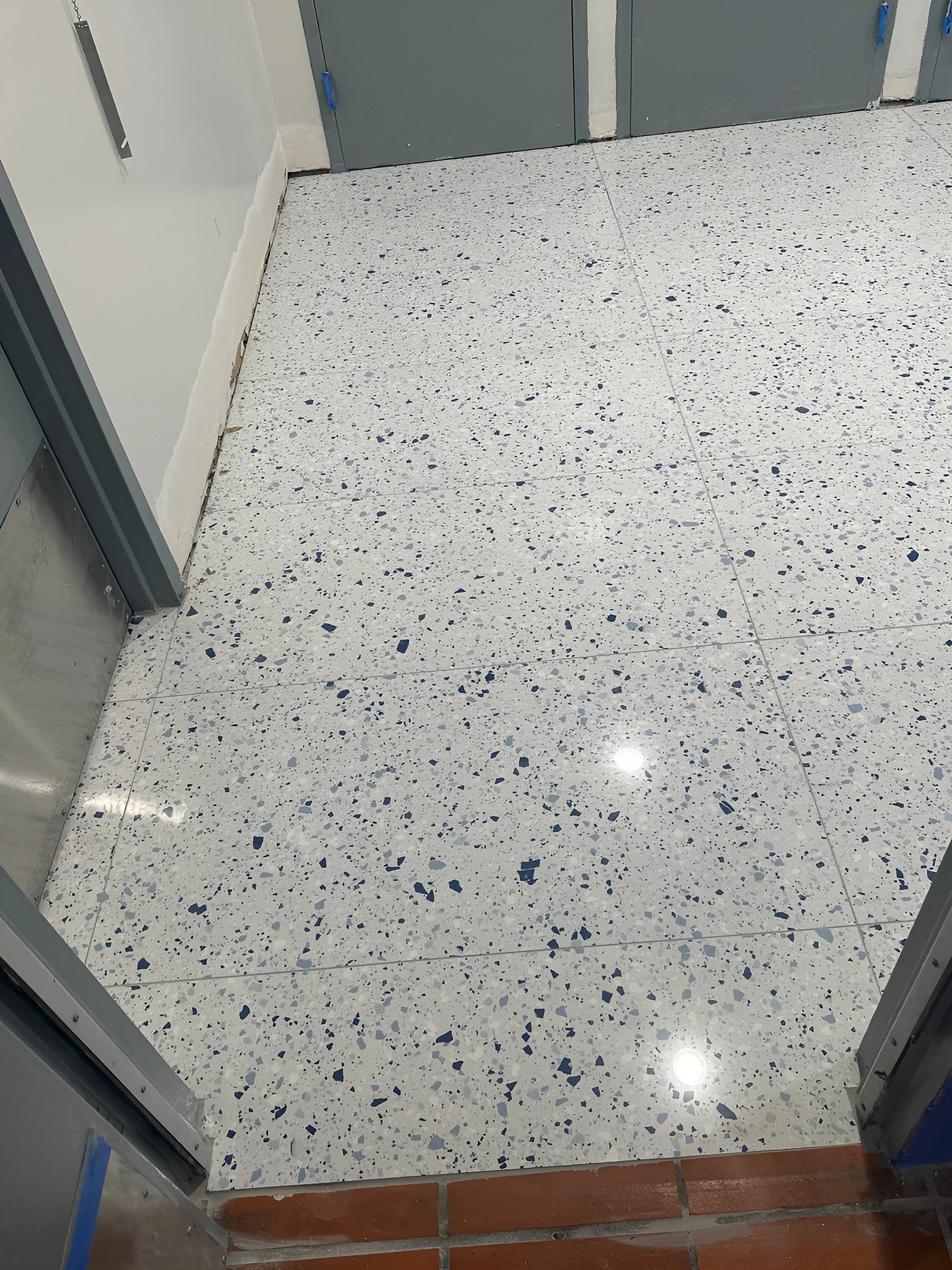 Baldosa blanca con aspecto de terrazo salpicada de azul