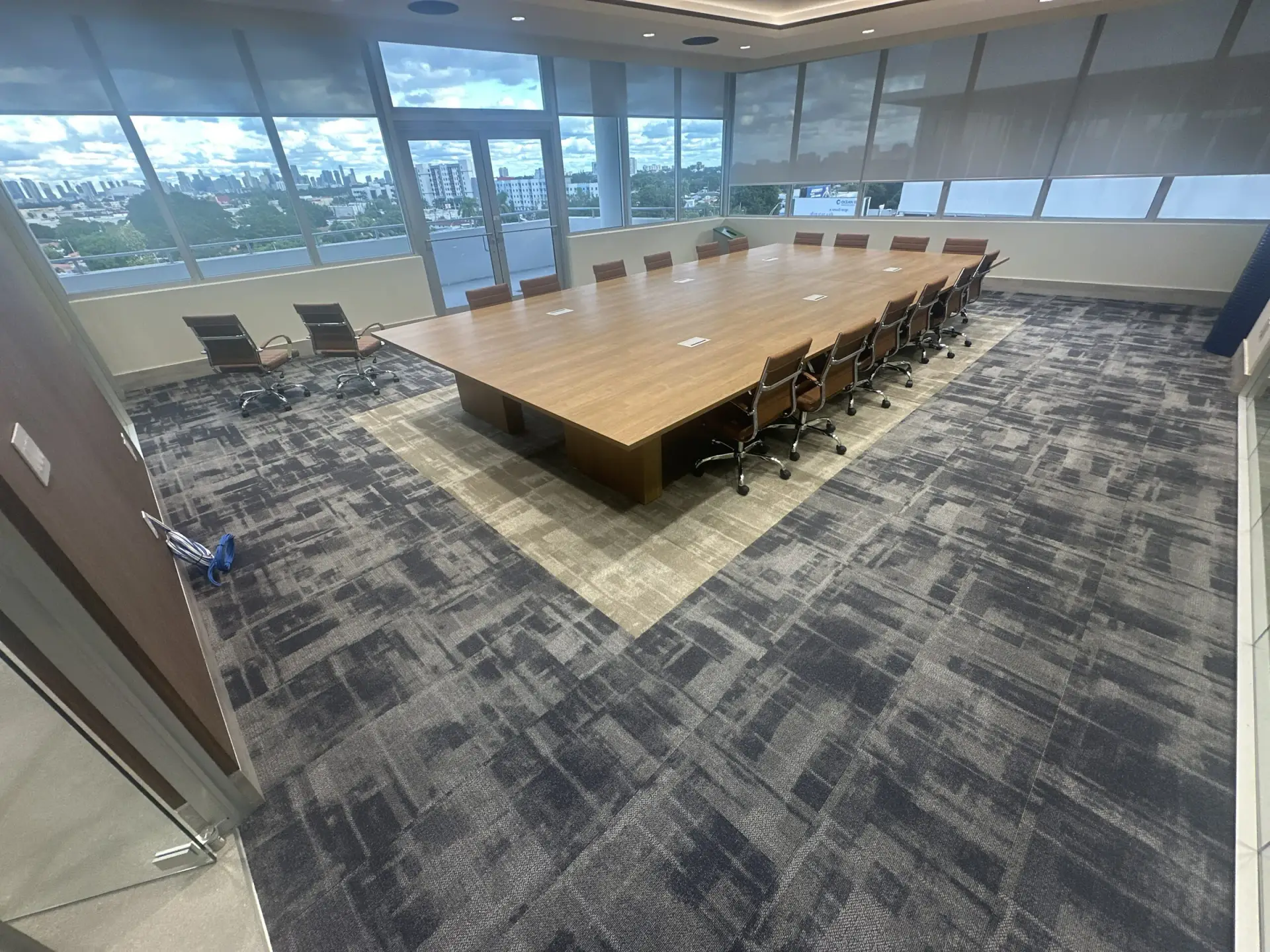 Mesa de juntas sobre alfombra gris azulado con un borde más claro