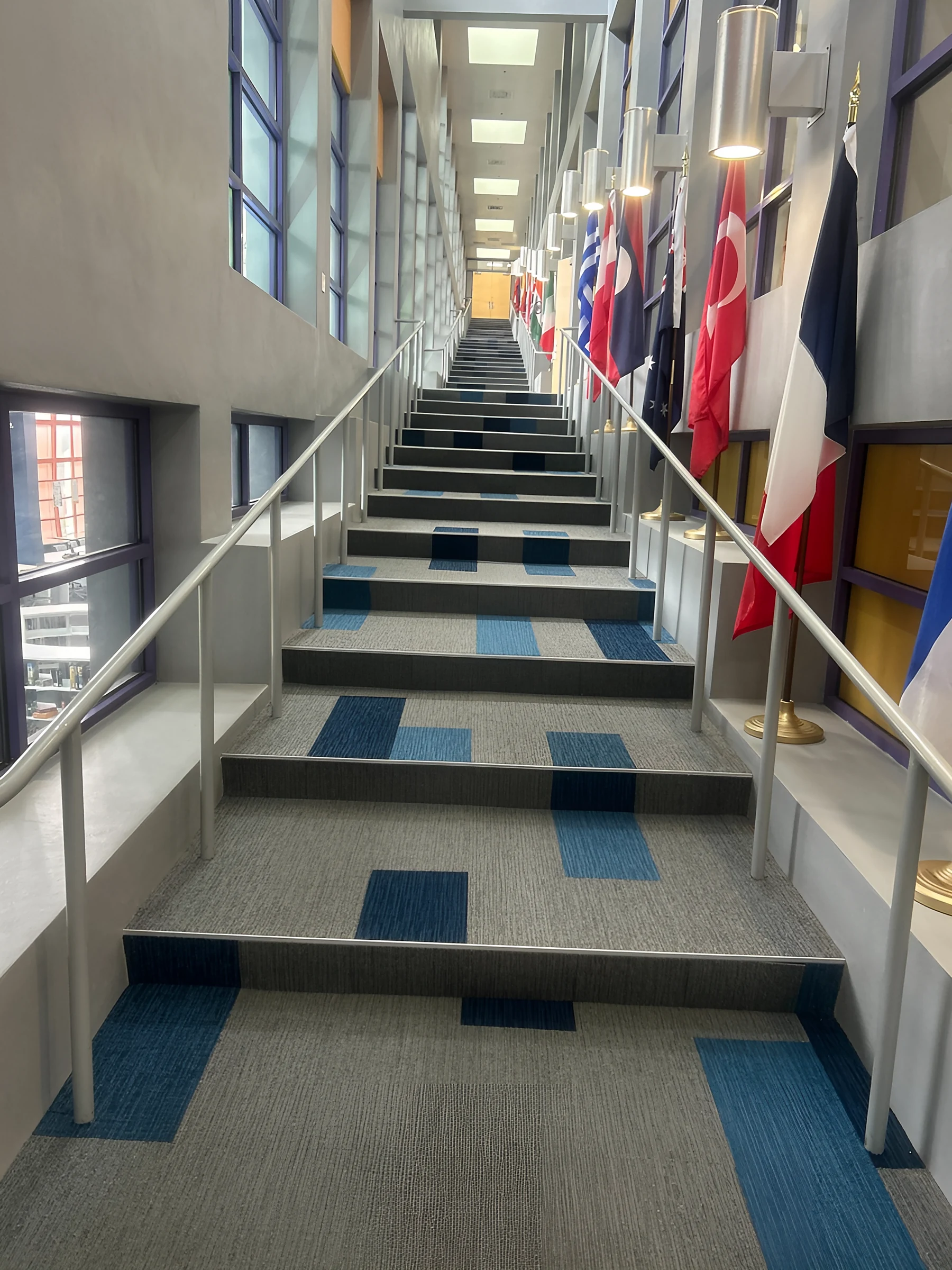 The grand stairwell, lined with international flags, carpeted tread by tread