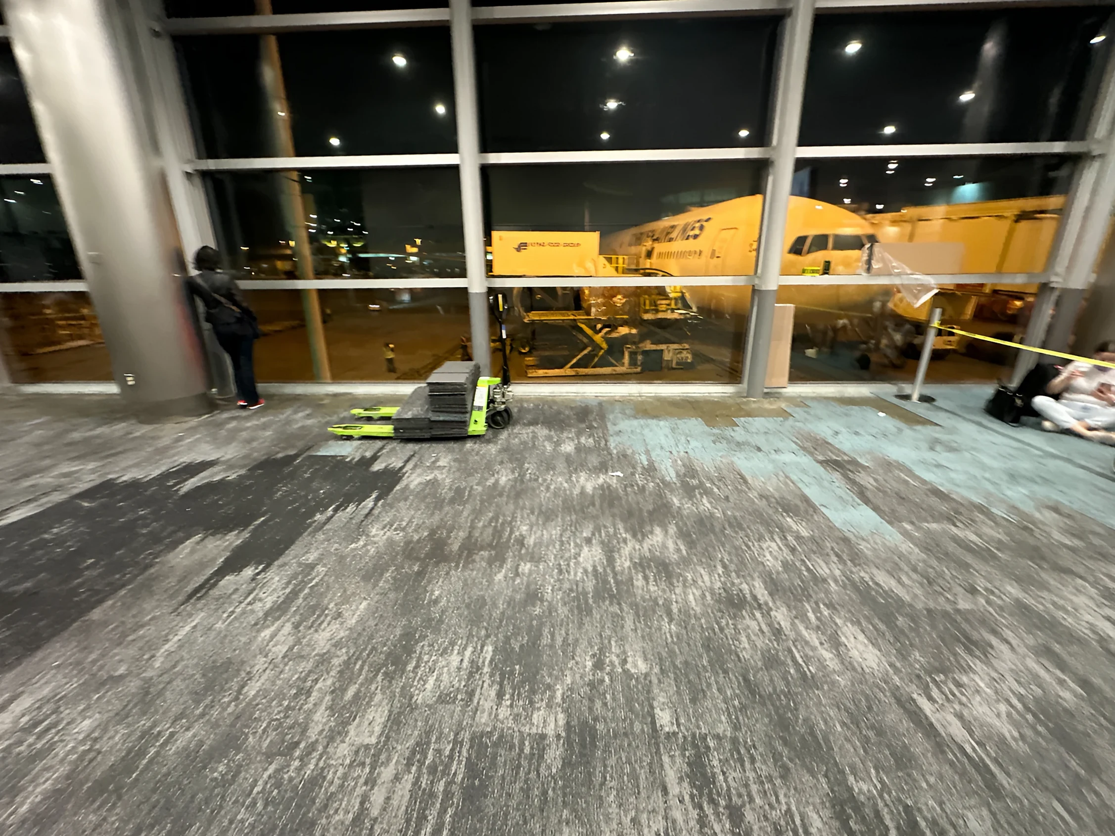 A finished gate area at night, with an aircraft parked beyond the windows