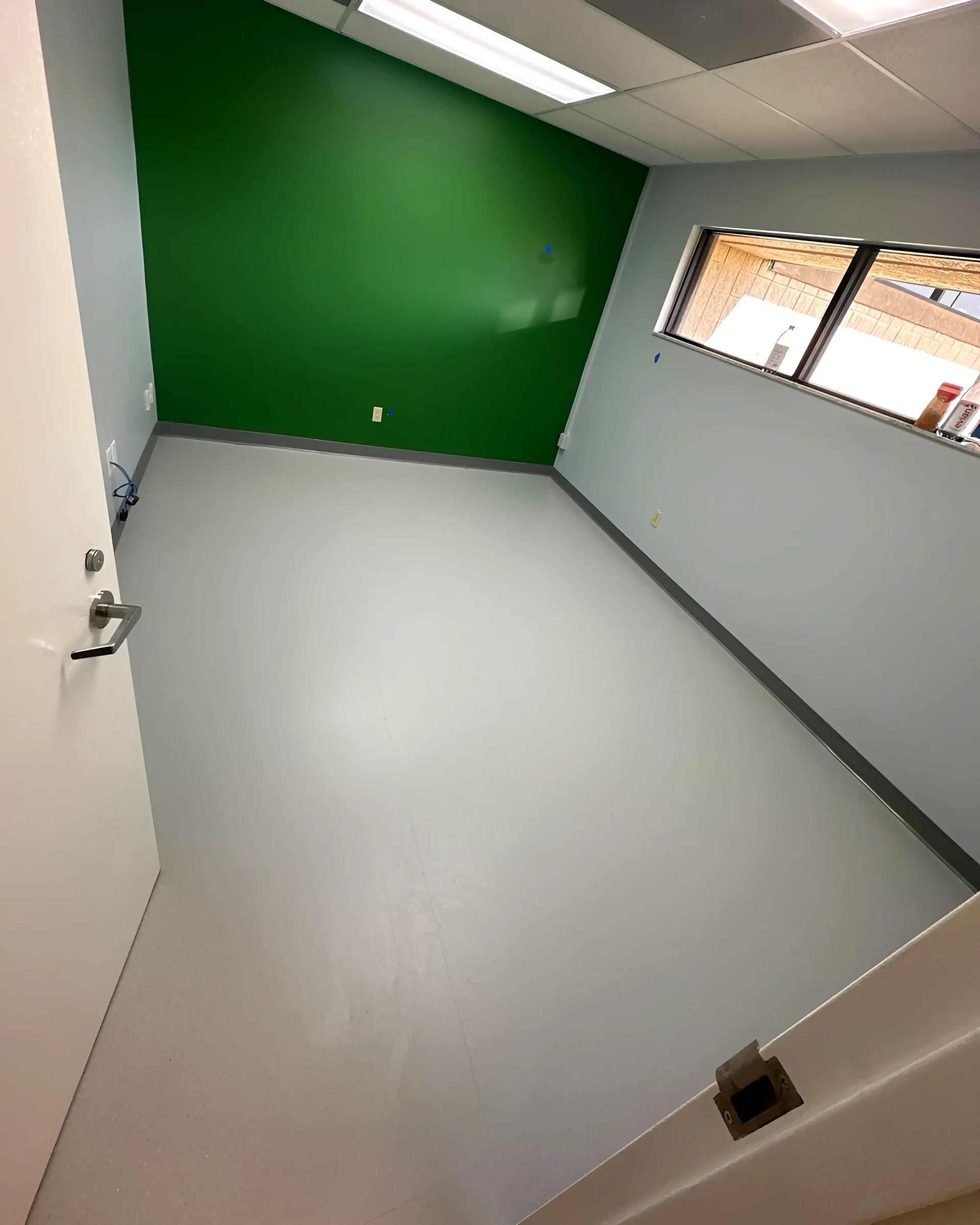 Room with a green accent wall over light rubber flooring
