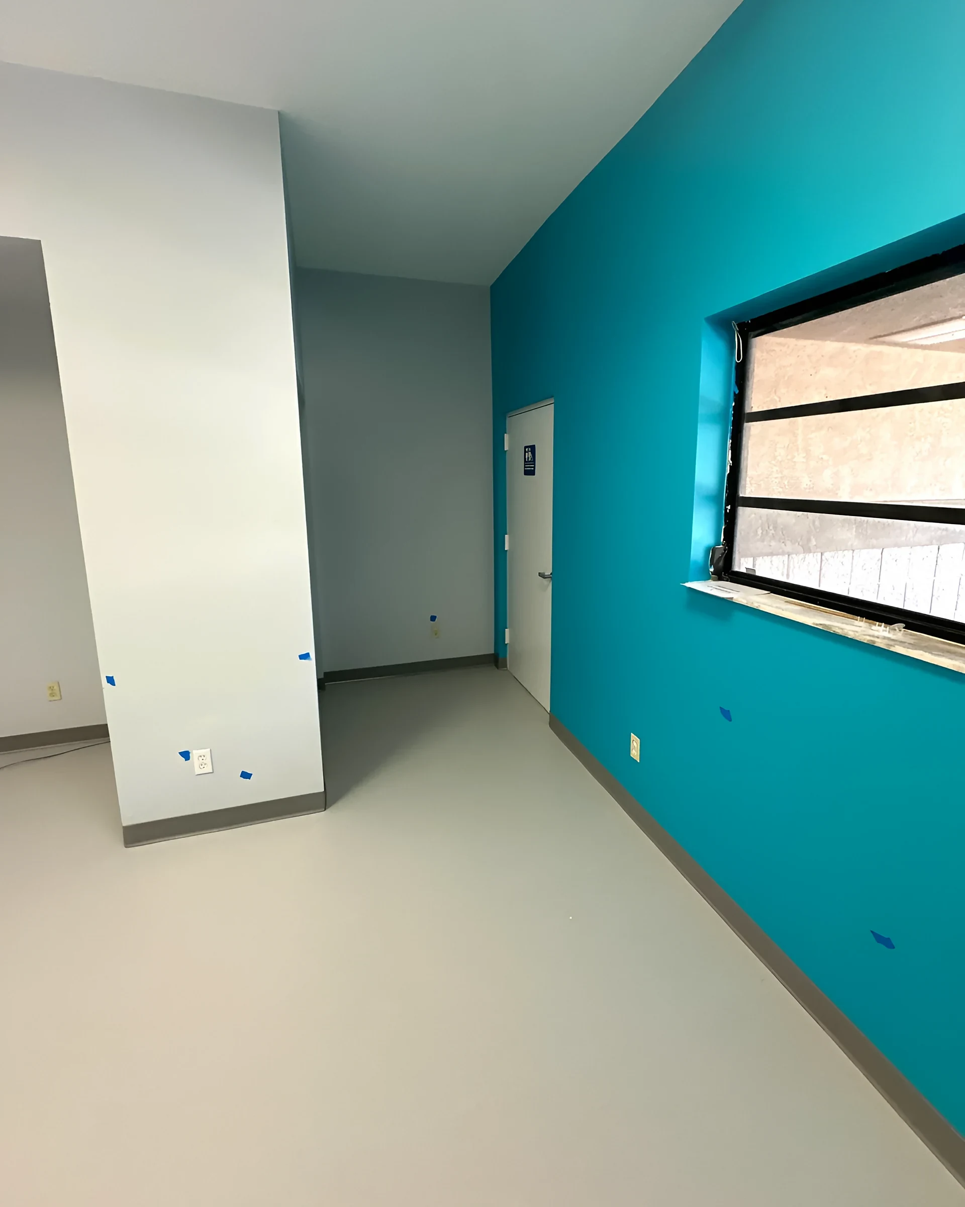 Teal wall and window over the new rubber tile