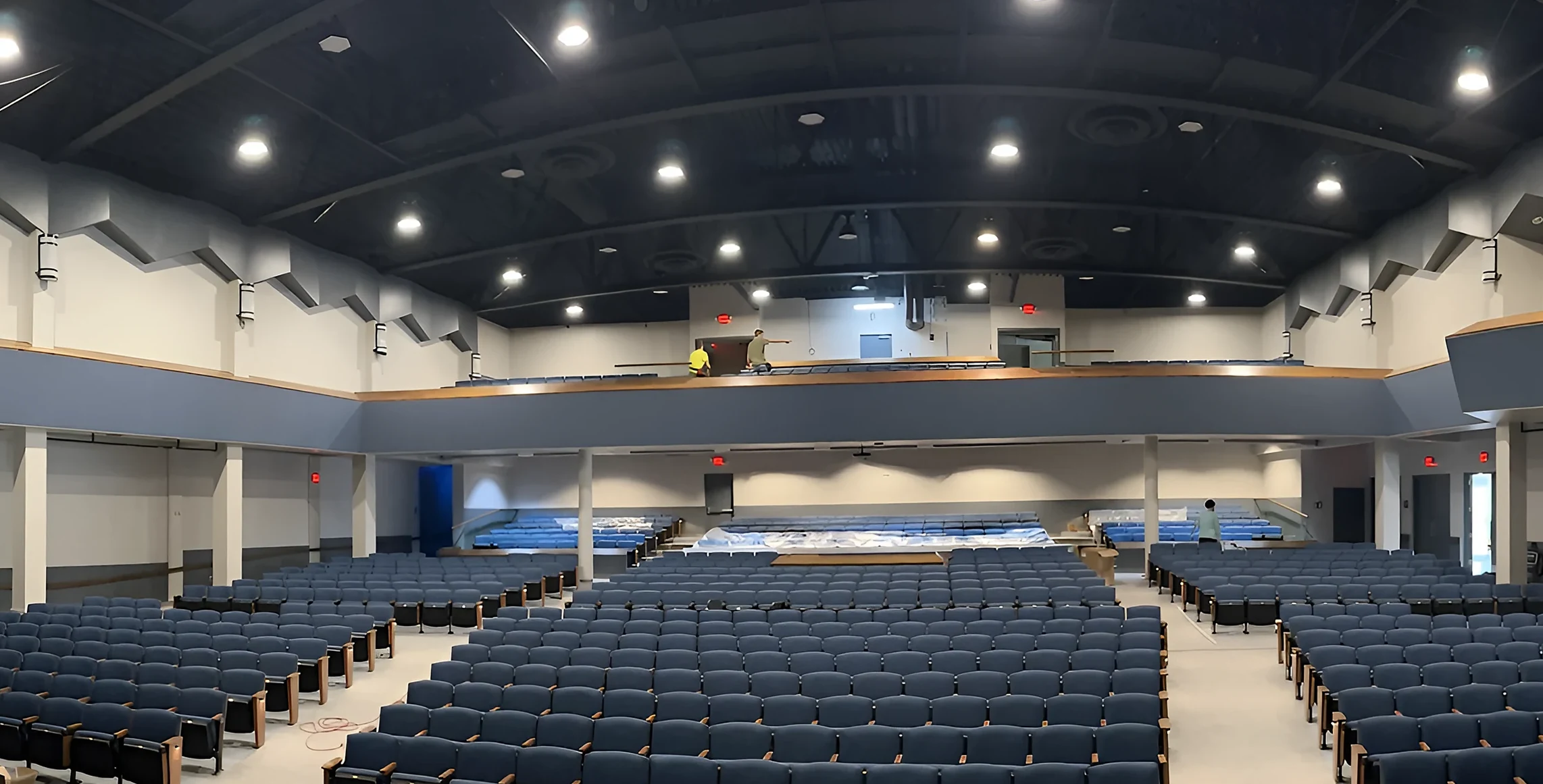 After: Lewis Auditorium with blue seating, light gray carpet tile and a navy balcony fascia with a maple cap