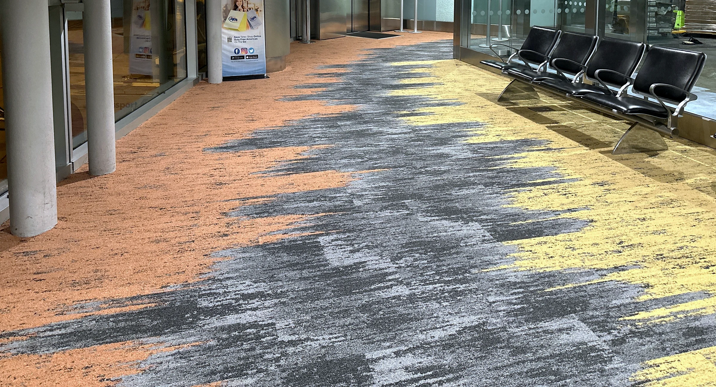 Coral and sun-yellow carpet waves in Concourse J at Miami International Airport