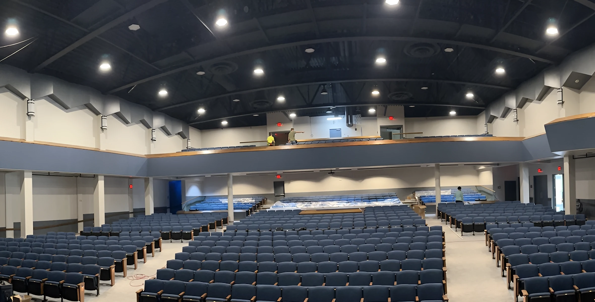 After: Lewis Auditorium with blue seating, light gray carpet tile and a navy balcony fascia with a maple cap