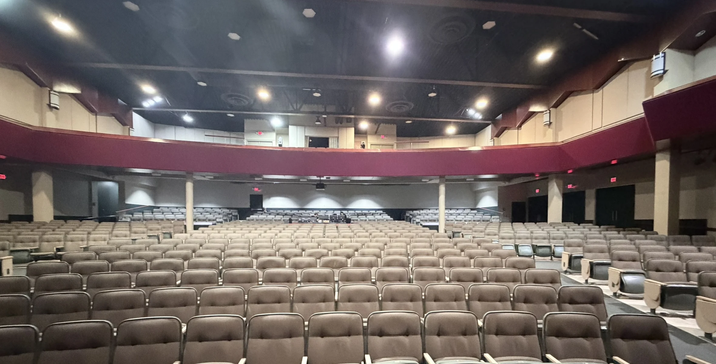 Before: Lewis Auditorium with beige seats, worn carpet and a maroon balcony fascia